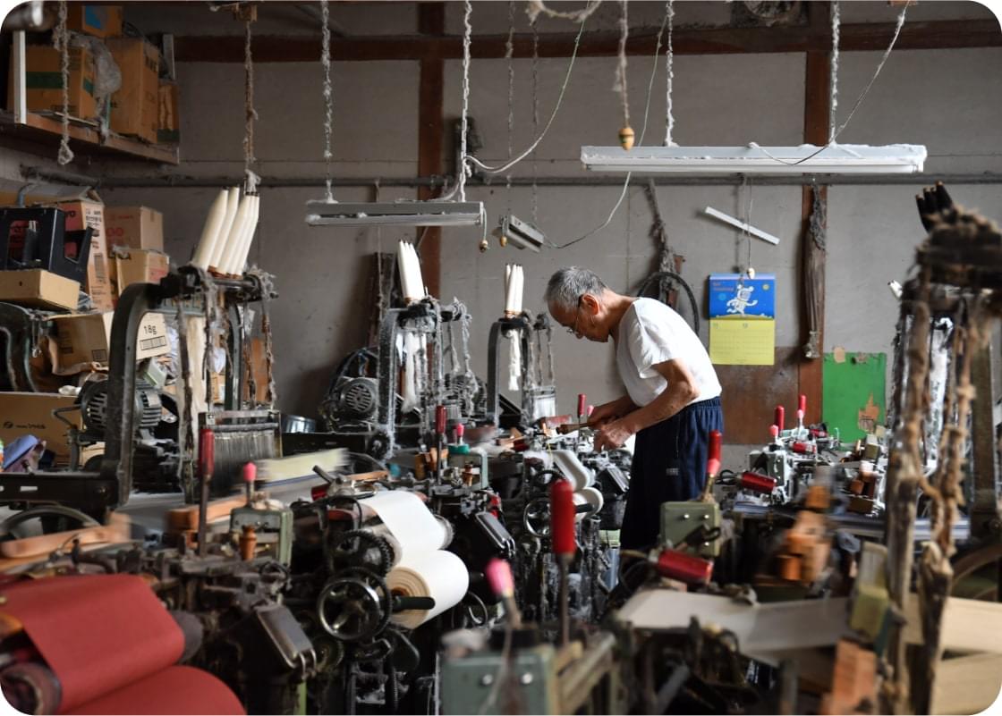 職人が織機（しょき）を操作する昔ながらの工場。