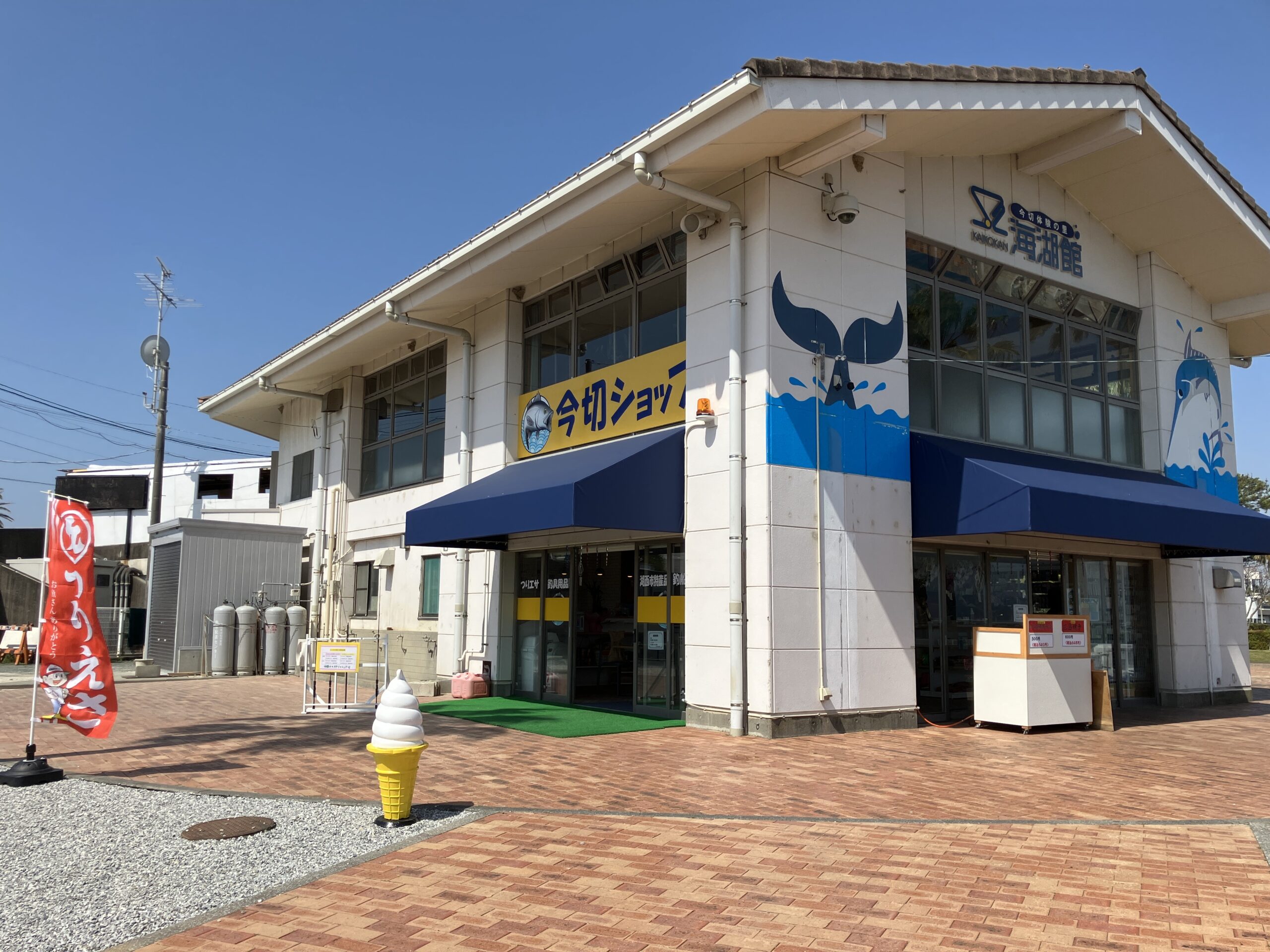 晴天の下に建つ海湖館（かいこかん）の白い2階建ての建物。